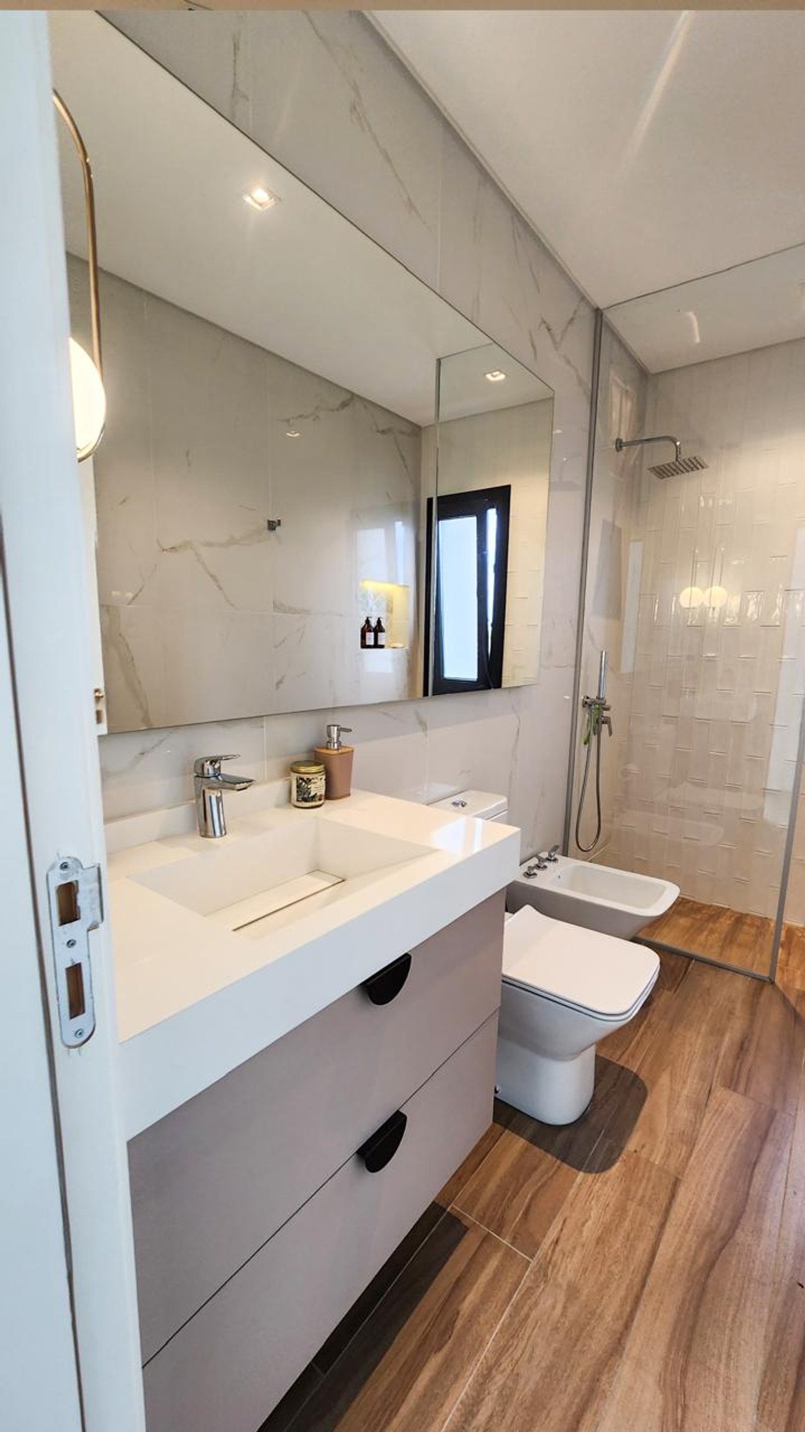 Baño moderno con vanitory flotante, mármol y madera — proyecto Canning, por Eniraestudio, en Canning